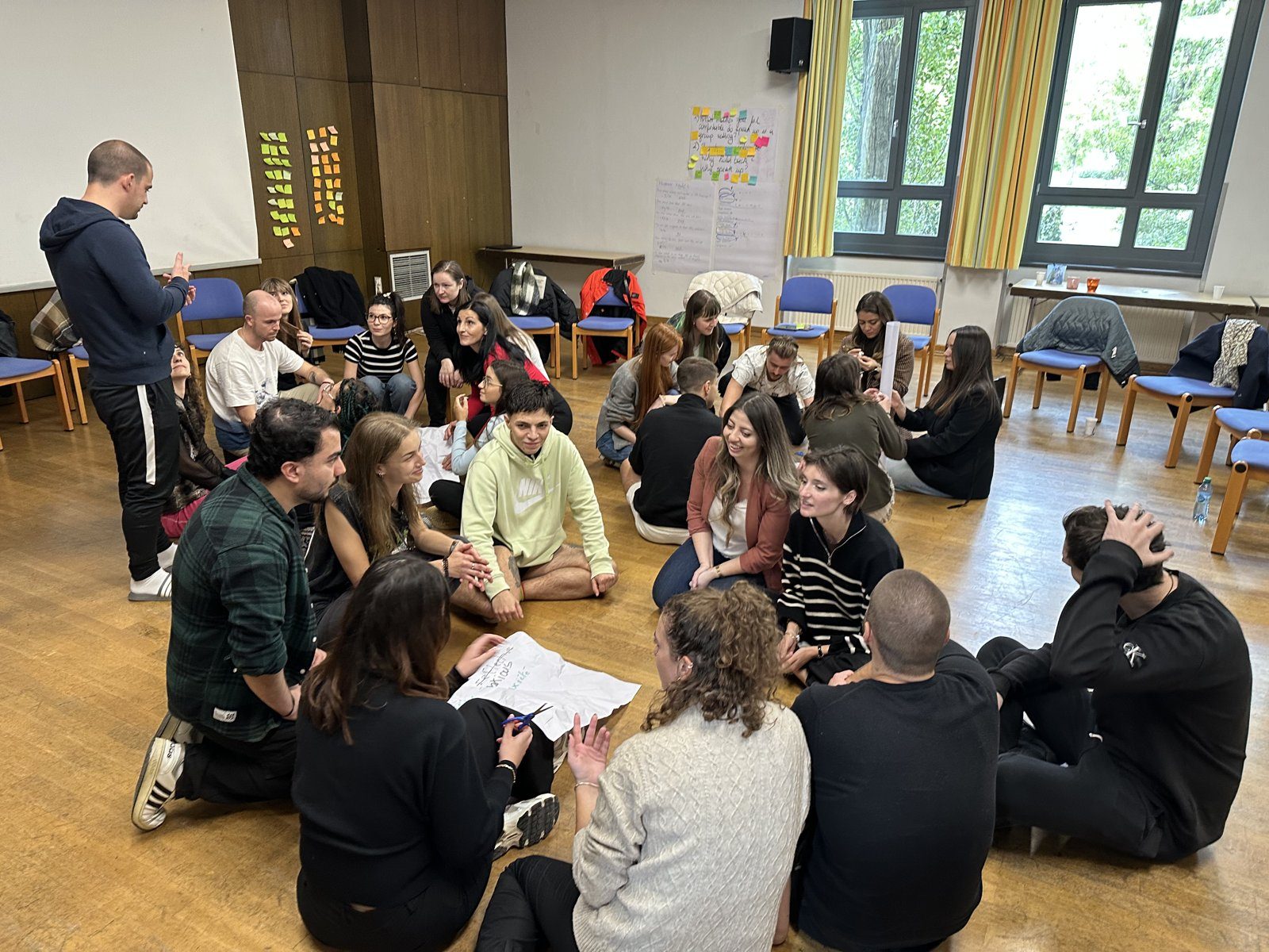 Participants of a youth exchange sitting on the floor in a circle around a facilitator