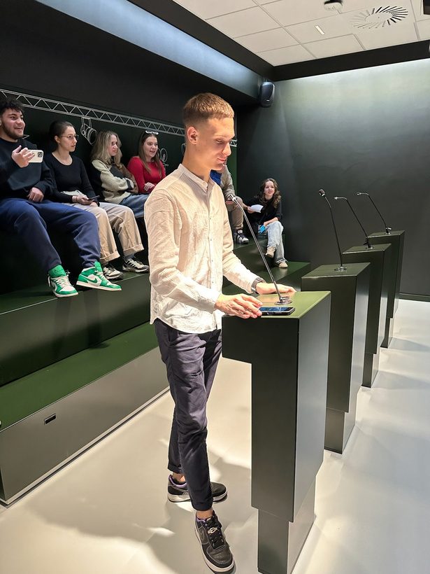 A young man speaking at a lectern while other participants listen during a Parliament simulation