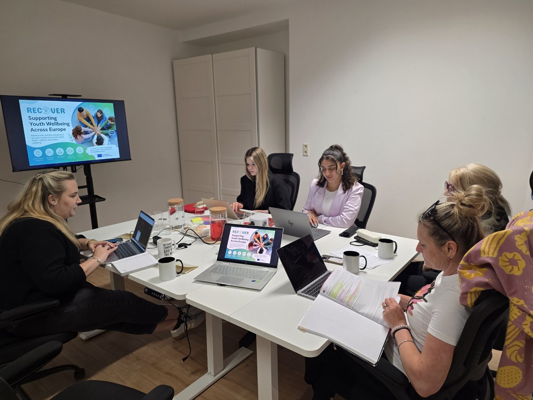 Team members working on laptops around a table during a project meeting