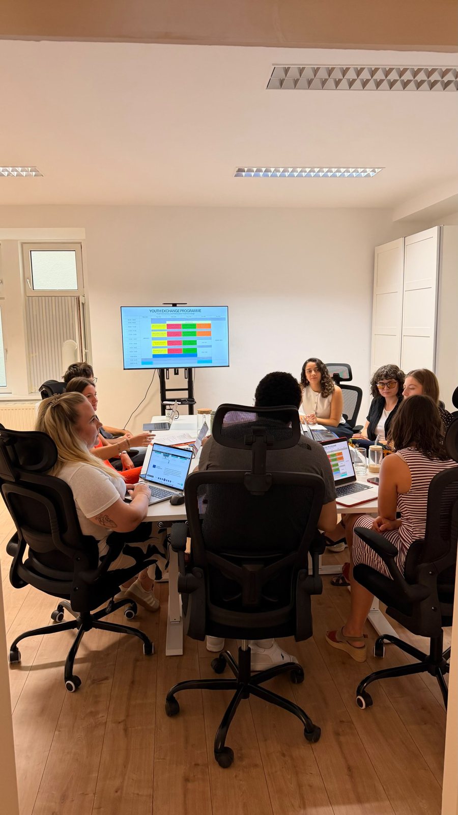The team planning a youth exchange programme shown on a large screen