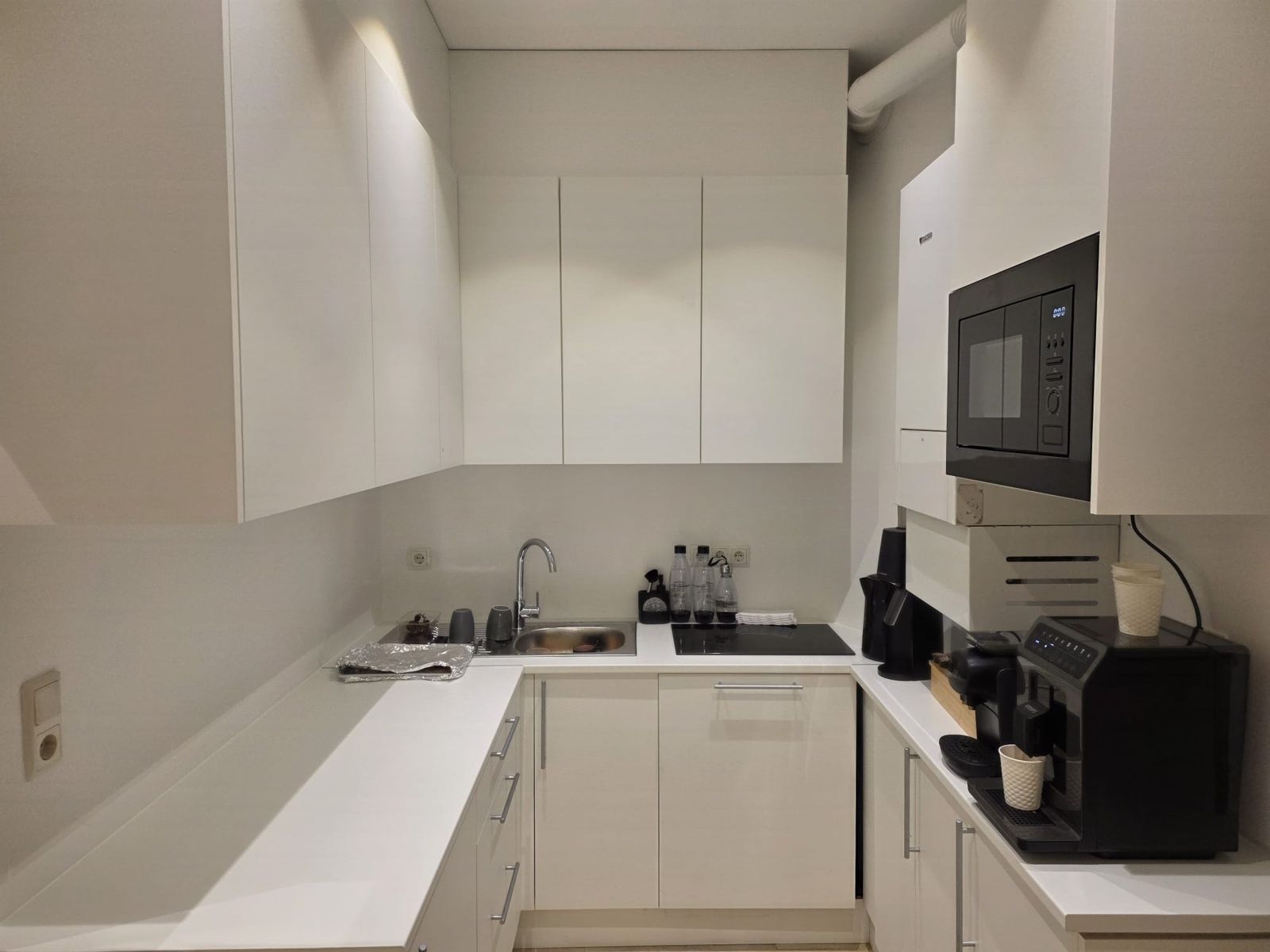 The kitchen with an espresso machine, kettle, microwave and hob