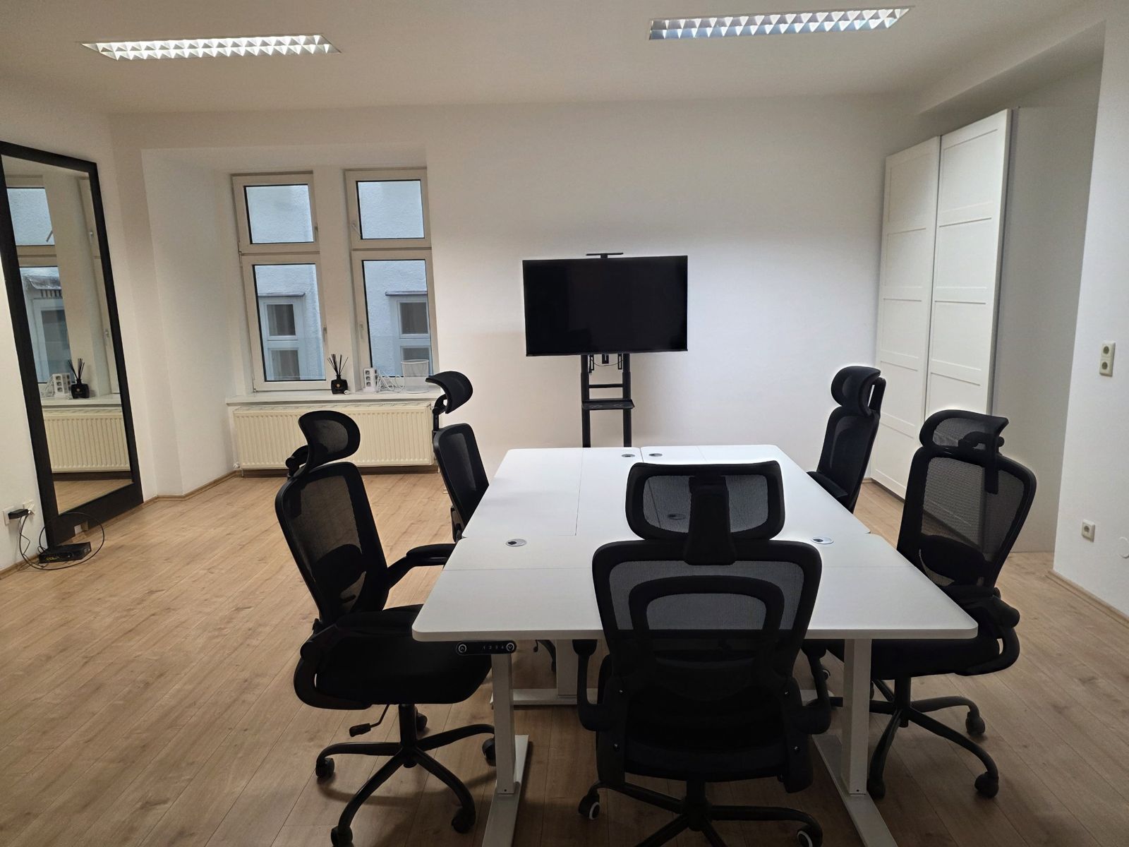 Raum 2 mit weißem Tisch, Bürostühlen und Bildschirm